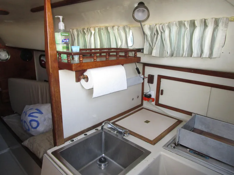 Slide: The Image of 1974 Irwin Competition 30 yacht interior with sink, storage, and curtains. - 13