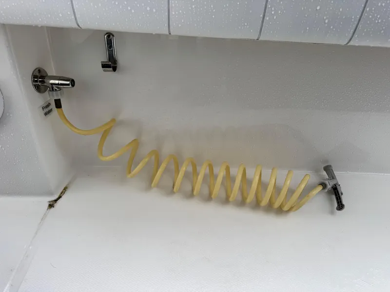 Slide: The Image of Yellow coiled hose in a 2019 Regulator 31 boat's washdown area. - 16
