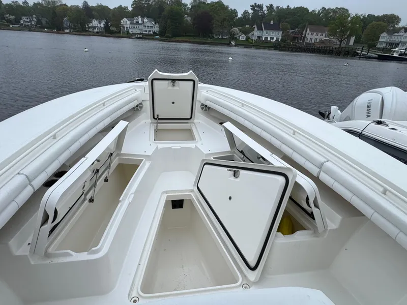 Slide: The Image of 2019 Regulator 31 boat with open storage compartments on a calm lake. - 19