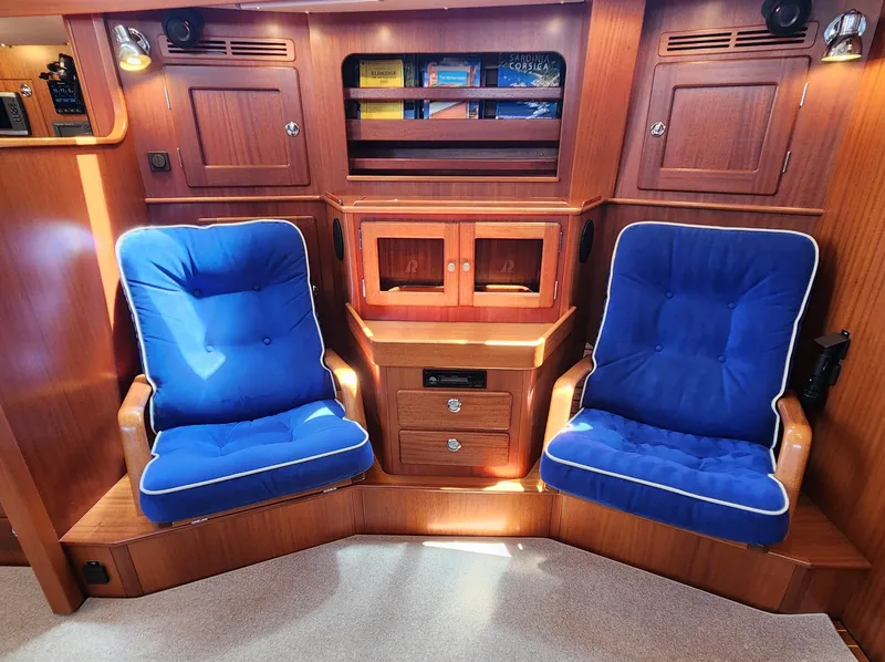 Slide: The Image of Luxurious 2006 Hallberg-Rassy 48 yacht interior with blue cushioned seating and wooden cabinetry. - 27