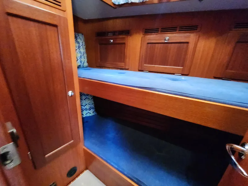 Slide: The Image of Interior of 2006 Hallberg-Rassy 48 yacht with wooden bunk beds and blue cushions. - 31