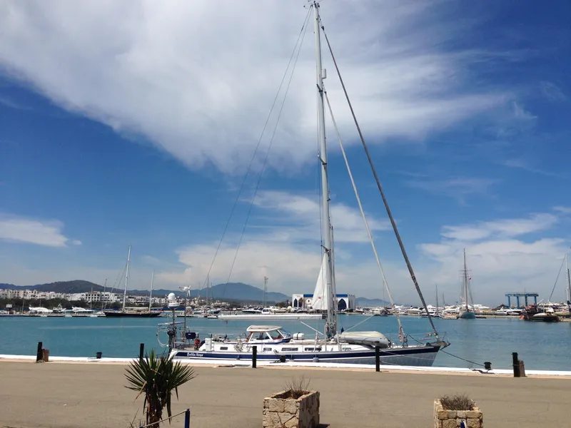 Slide: The Image of 2006 Hallberg-Rassy 48 yacht docked in a scenic marina under a blue sky. - 5