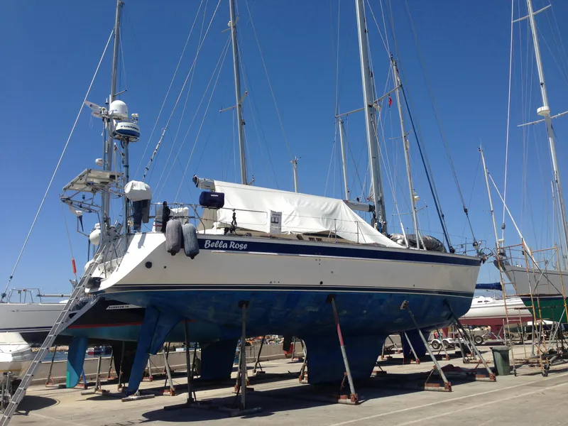 Slide: The Image of Hallberg-Rassy 48 sailboat from 2006 on dry dock, blue hull, clear sky background. - 6