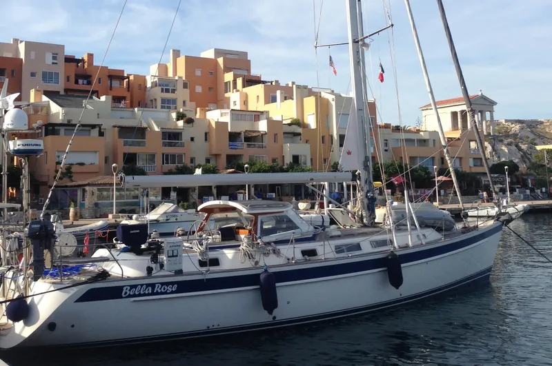 Slide: The Image of 2006 Hallberg-Rassy 48 sailboat docked in a marina with colorful buildings in the background. - 9