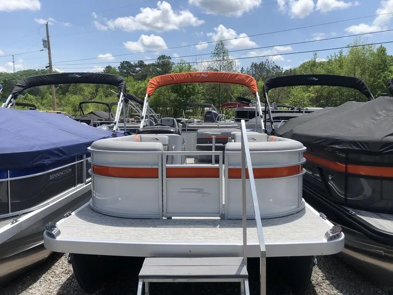 Slide: The Image of 2025 Bennington SX L-Bench 22 SXL pontoon boat with orange canopy, parked outdoors. - 3