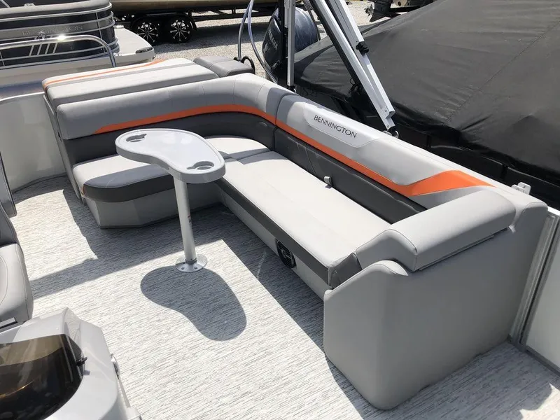 Slide: The Image of 2025 Bennington SX L-Bench 22 SXL pontoon boat seating with table, featuring gray and orange accents. - 4