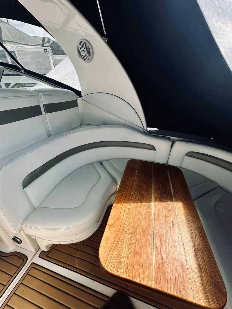 Slide: The Image of 2006 Sea Ray 320 Sundancer interior with curved seating and wooden table. - 13