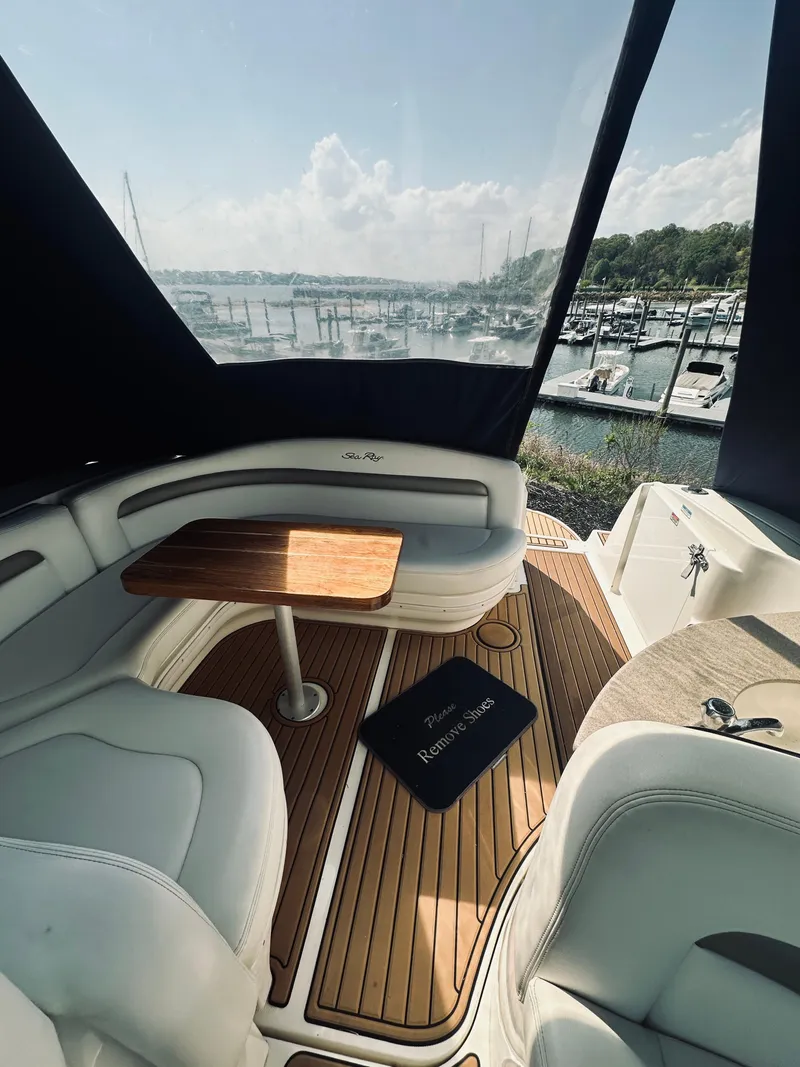 Slide: The Image of 2006 Sea Ray 320 Sundancer interior with wood table, marina view, and cushioned seating. - 14