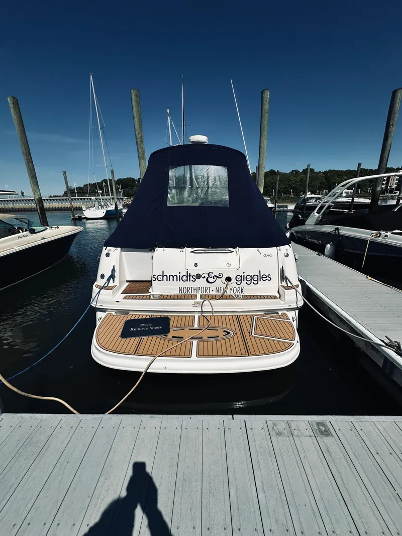 Slide: The Image of 2006 Sea Ray 320 Sundancer docked at marina, rear view with blue cover. - 2