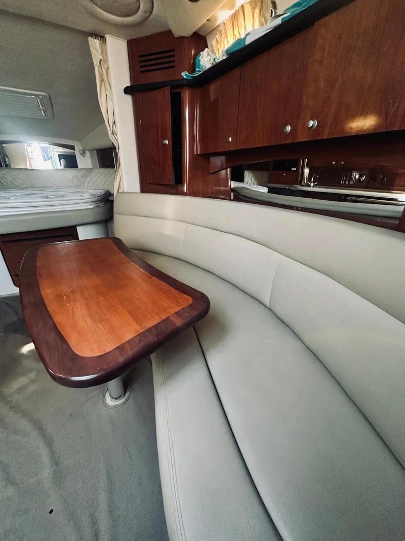 Slide: The Image of Interior of 2006 Sea Ray 320 Sundancer with curved seating and wooden table. - 23