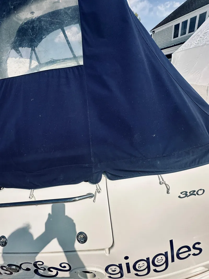 Slide: The Image of 2006 Sea Ray 320 Sundancer boat with navy cover, docked near a house. - 9