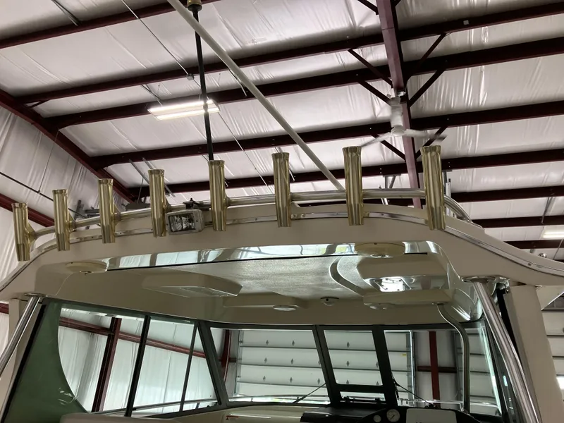 Slide: The Image of 2012 Striper 2901 Walkaround I/O boat in storage, showcasing rod holders and cabin roof. - 13