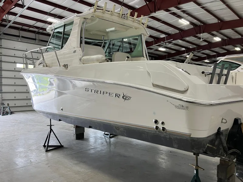 Slide: The Image of 2012 Striper 2901 Walkaround I/O boat in a warehouse, elevated on stands. - 2
