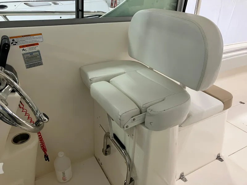 Slide: The Image of 2012 Striper 2901 Walkaround I/O helm seat with white cushioned design and steering wheel. - 22