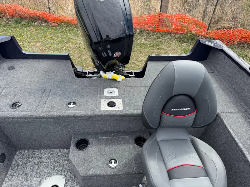 Slide: The Image of 2025 Tracker Pro Guide V-175 WT boat interior with gray seating and motor, outdoors. - 11