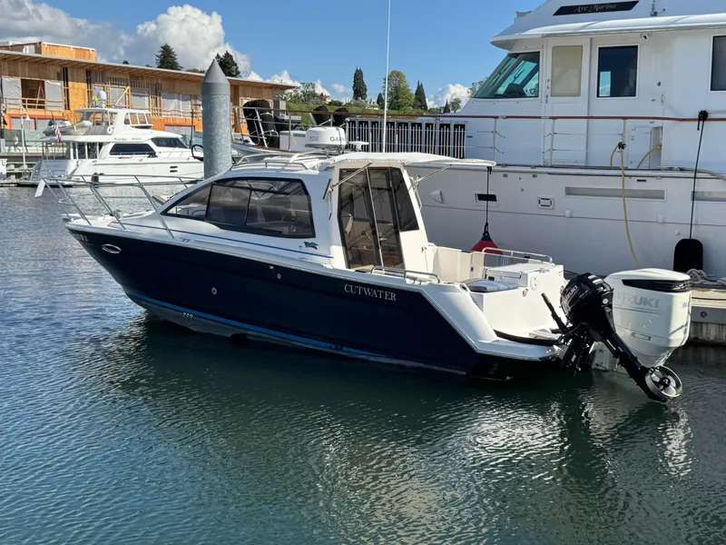 Slide: The Image of 2018 Cutwater C-242 Coupe boat docked at a marina, featuring sleek design and outboard motor. - 1