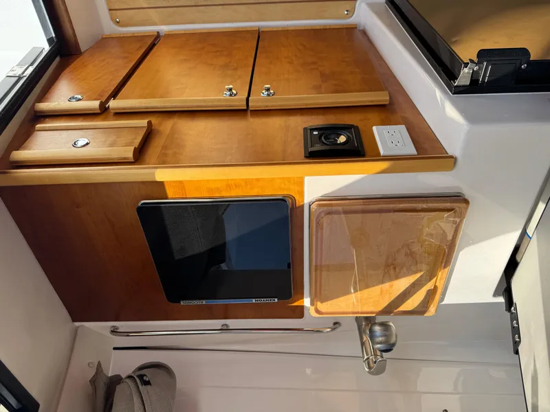Slide: The Image of 2018 Cutwater C-242 Coupe interior with wooden cabinetry and compact kitchen setup. - 11