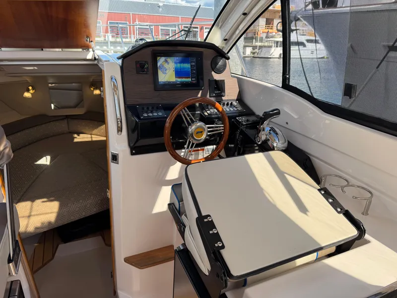 Slide: The Image of 2018 Cutwater C-242 Coupe interior with helm, navigation screen, and cozy cabin area. - 13