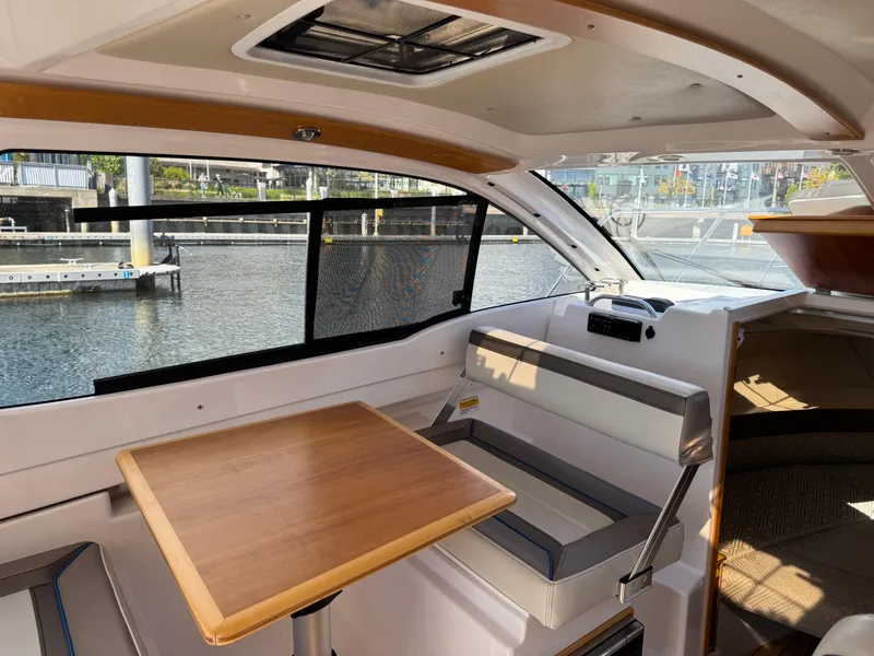 Slide: The Image of Interior of 2018 Cutwater C-242 Coupe boat with seating and table by a window. - 18