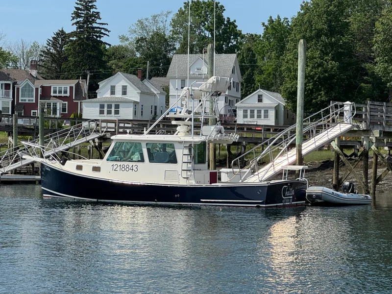 Slide: The Image of 2009 Northern Bay 36 boat docked near waterfront homes, with lush greenery in the background. - 2