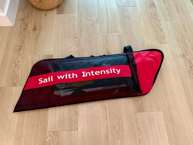 Slide: The Image of Red and black sail bag on wooden floor, labeled "Sail with Intensity," for Dinghy PSA ILCA 6. - 5