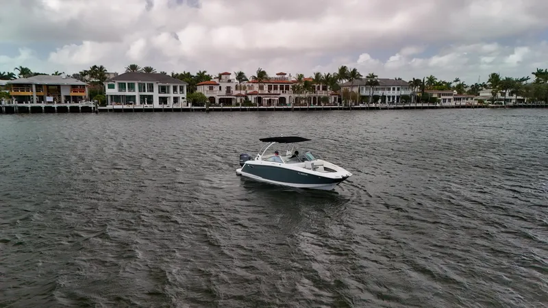 Slide: The Image of 2021 Cobalt 25SC boat cruising near waterfront homes under cloudy skies. - 12