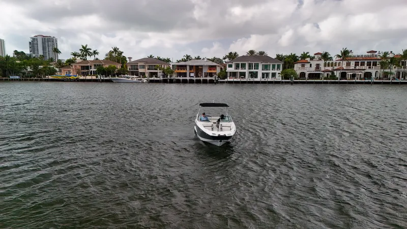 Slide: The Image of 2021 Cobalt 25SC boat cruising on a scenic waterfront with luxury homes in the background. - 13