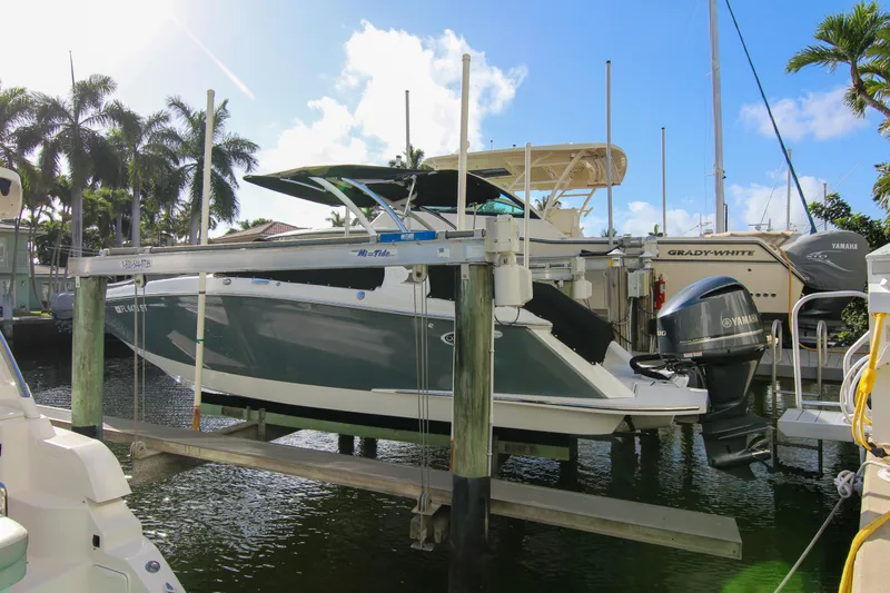Slide: The Image of 2021 Cobalt 25SC boat docked, surrounded by palm trees and clear blue sky. - 23