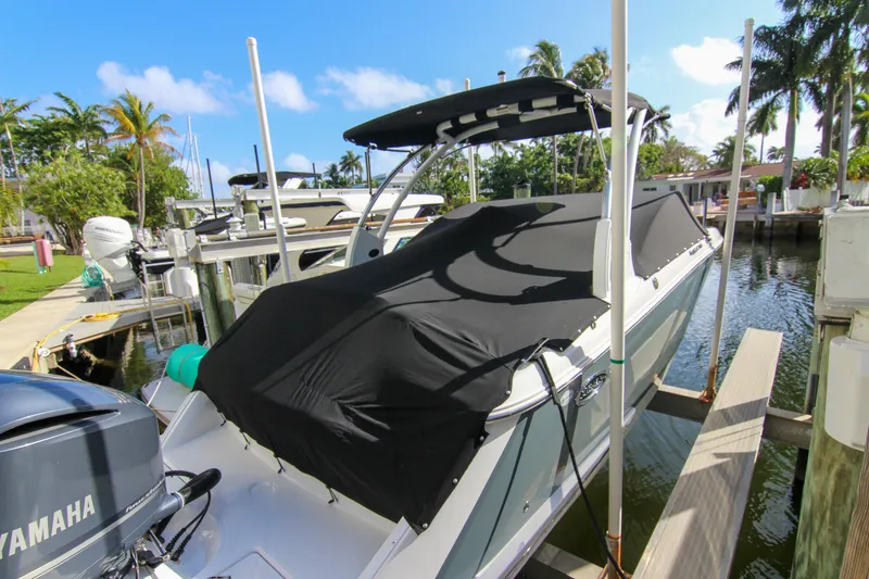 Slide: The Image of 2021 Cobalt 25SC boat docked, covered, with Yamaha outboard motor, surrounded by palm trees. - 26