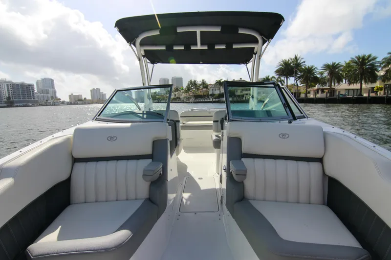 Slide: The Image of 2021 Cobalt 25SC boat interior with plush seating, open water view, and city skyline backdrop. - 34