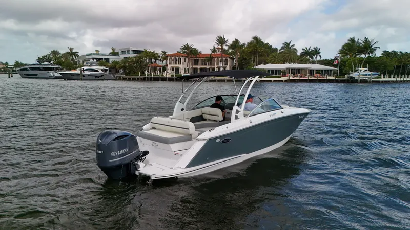 Slide: The Image of 2021 Cobalt 25SC boat cruising on a scenic waterfront with luxury homes. - 8