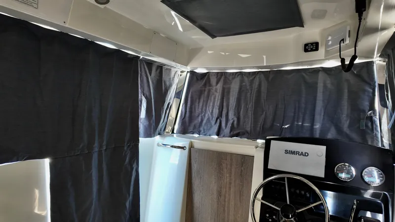 Slide: The Image of Interior of 2025 Bayliner Trophy 23 Pilothouse with curtains and Simrad navigation system. - 10
