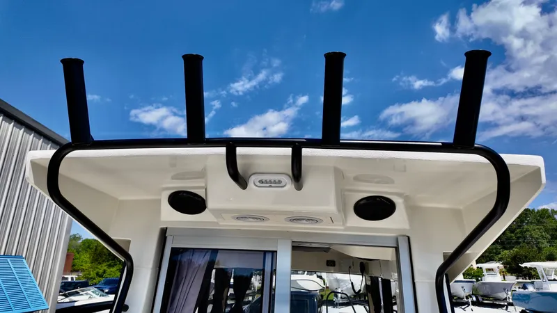 Slide: The Image of Bayliner Trophy 23 Pilothouse 2025, rear view with rod holders, under a clear blue sky. - 15