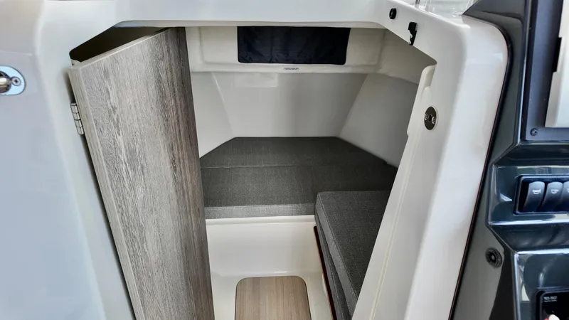 Slide: The Image of 2025 Bayliner Trophy 23 Pilothouse cabin interior with wood door and cushioned seating. - 22