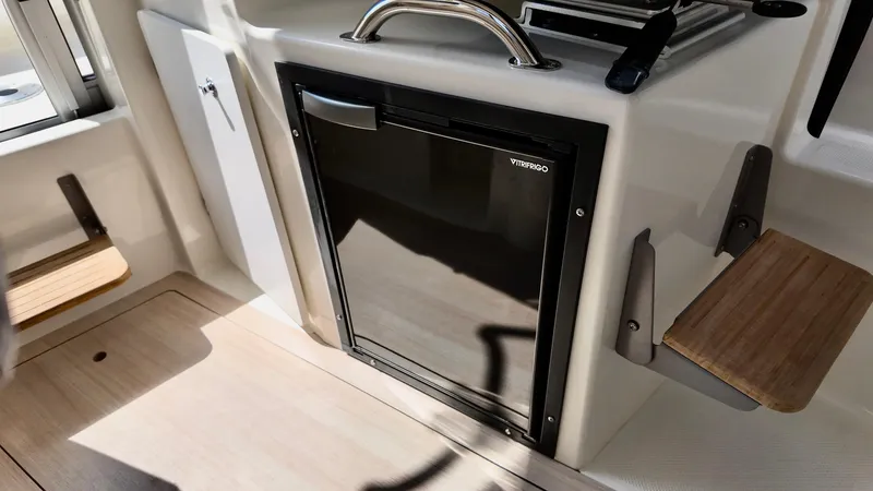 Slide: The Image of 2025 Bayliner Trophy 23 Pilothouse interior with compact fridge and seating. - 25