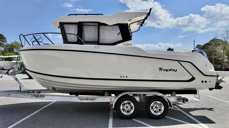 Slide: The Image of 2025 Bayliner Trophy 23 Pilothouse boat on trailer, parked outdoors under blue sky. - 4