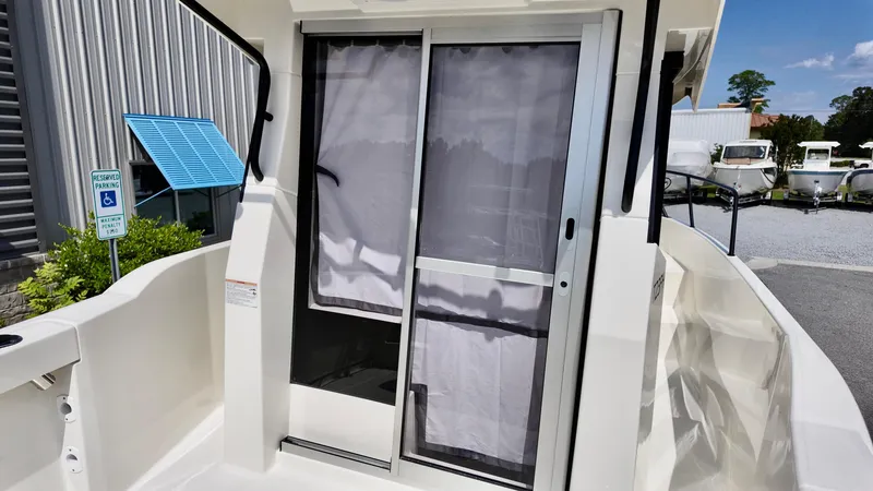 Slide: The Image of 2025 Bayliner Trophy 23 Pilothouse boat with sliding door and curtain, docked outdoors. - 8