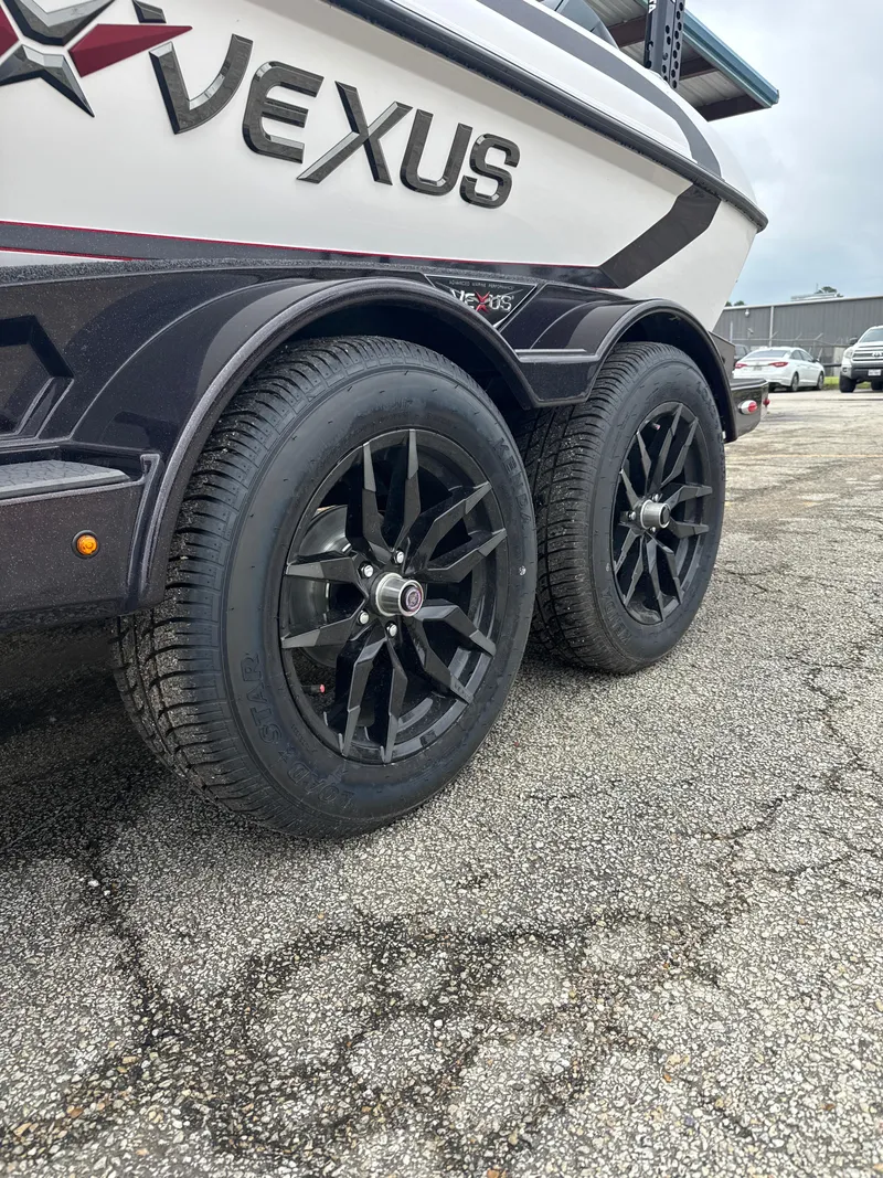 Slide: The Image of 2025 Vexus VXS20 trailer with black alloy wheels on a paved surface. - 7