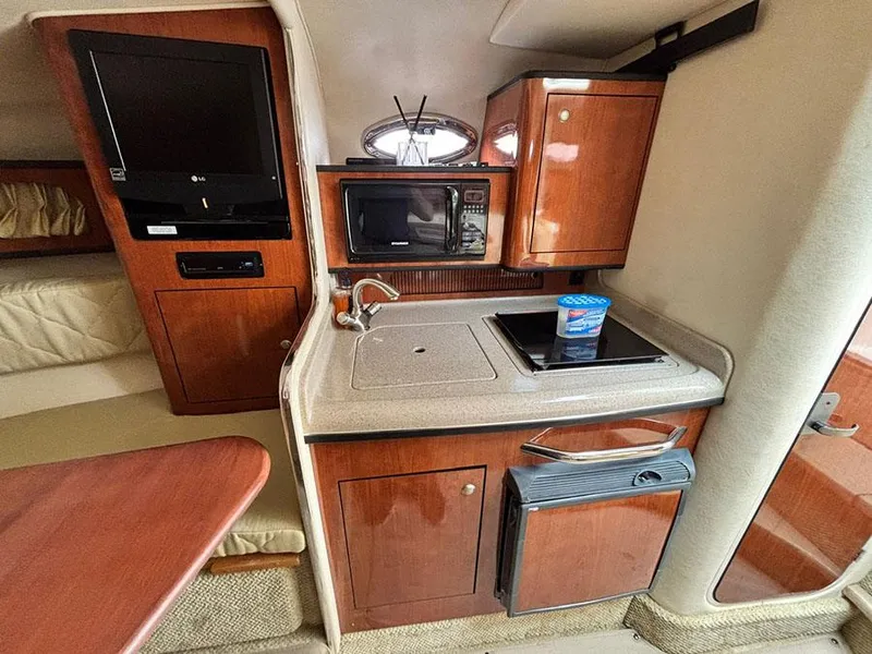Slide: The Image of 2007 Sea Ray 280 Sundancer interior with kitchenette, featuring wood cabinets and modern appliances. - 16