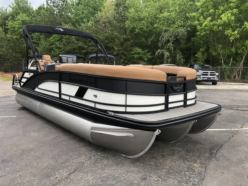 Slide: The Image of 2025 Bennington M L-Bench 22ML pontoon boat with tan seating, parked outdoors. - 1