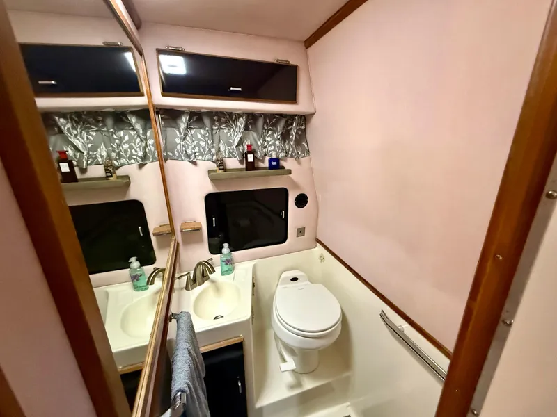 Slide: The Image of 1989 Sea Ray 340 Sundancer bathroom with sink, toilet, and mirror. - 13