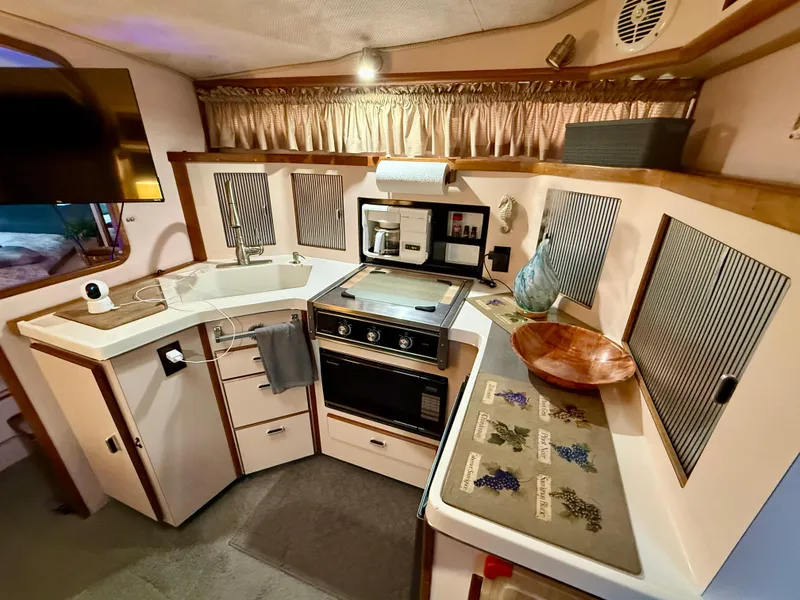Slide: The Image of 1989 Sea Ray 340 Sundancer kitchen with stove, sink, and modern amenities. - 2