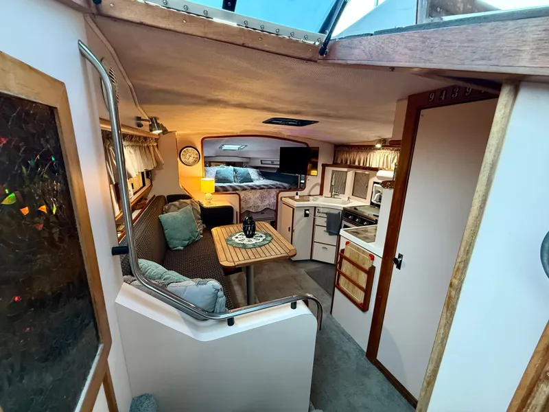 Slide: The Image of 1989 Sea Ray 340 Sundancer cabin interior with cozy seating, kitchenette, and sleeping area. - 3