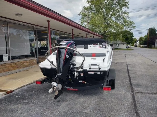 Slide: The Image of 2024 Tahoe T18 boat on trailer, parked outside a building, rear view. - 3