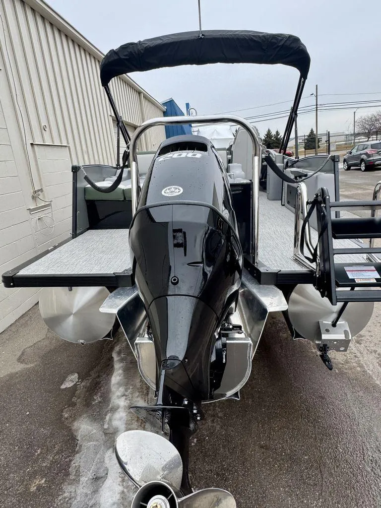 Slide: The Image of 2025 Tahoe Cascade 2385 VRB pontoon boat with sleek black motor, docked outdoors. - 2