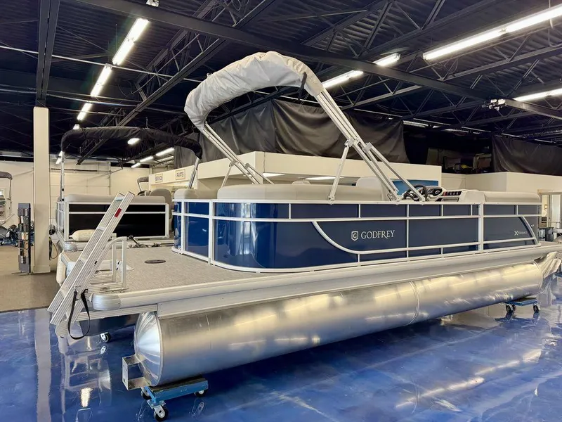 Slide: The Image of 2025 Godfrey EX 2286 SBX pontoon boat displayed in a showroom. - 2