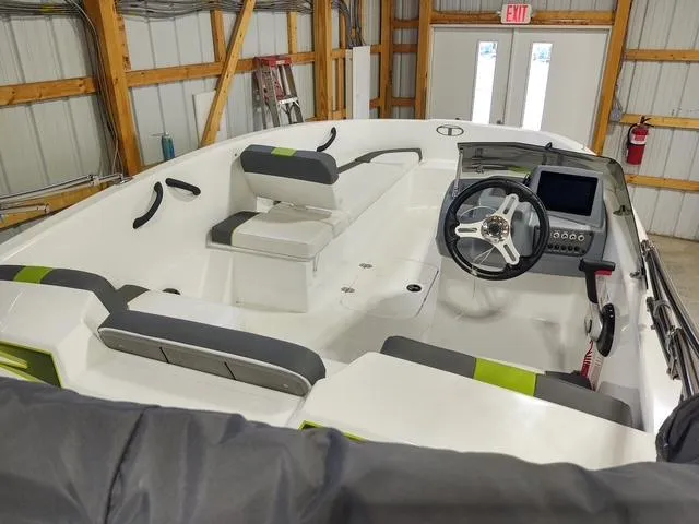 Slide: The Image of 2023 Tahoe T16 boat interior with modern dashboard and seating in a storage facility. - 7