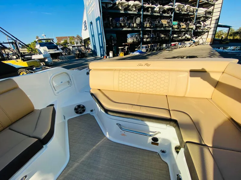 Slide: The Image of 2022 Sea Ray 270 SDX boat interior with tan seating and outdoor marina view. - 13