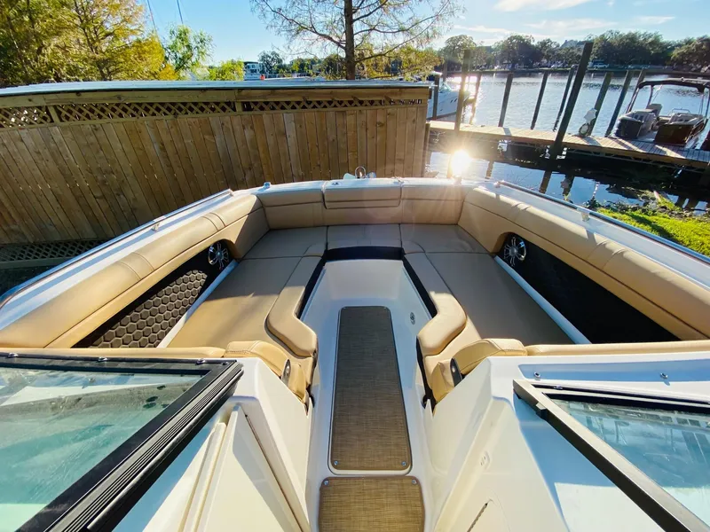 Slide: The Image of 2022 Sea Ray 270 SDX boat interior with tan seating, docked by a sunny lakeside. - 21