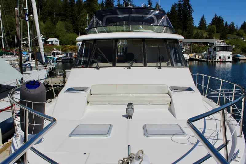 Slide: The Image of 1999 Bayliner 4788 Motoryacht docked in a marina with scenic forest backdrop. - 17
